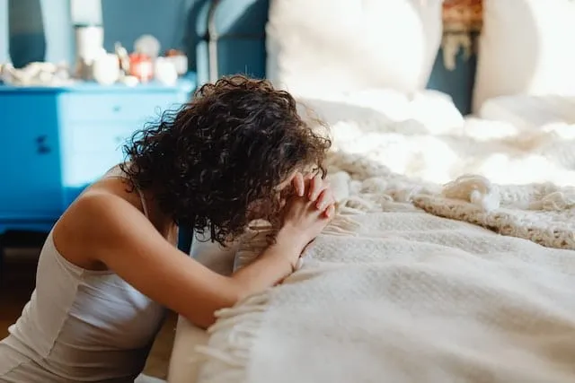 A woman praying in front of her bed for spiritual relationship with Jesus