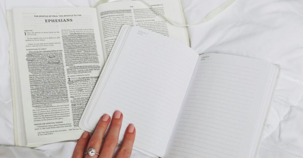 An open Bible displaying the book of Ephesians alongside a blank journal, offering a reflective setup for those learning how to start reading the Bible and taking notes during their spiritual journey.