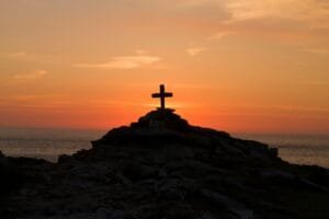 A cross silhouette on a mountain during golden hour, symbolizing faith, hope, and God's grace in difficult times.